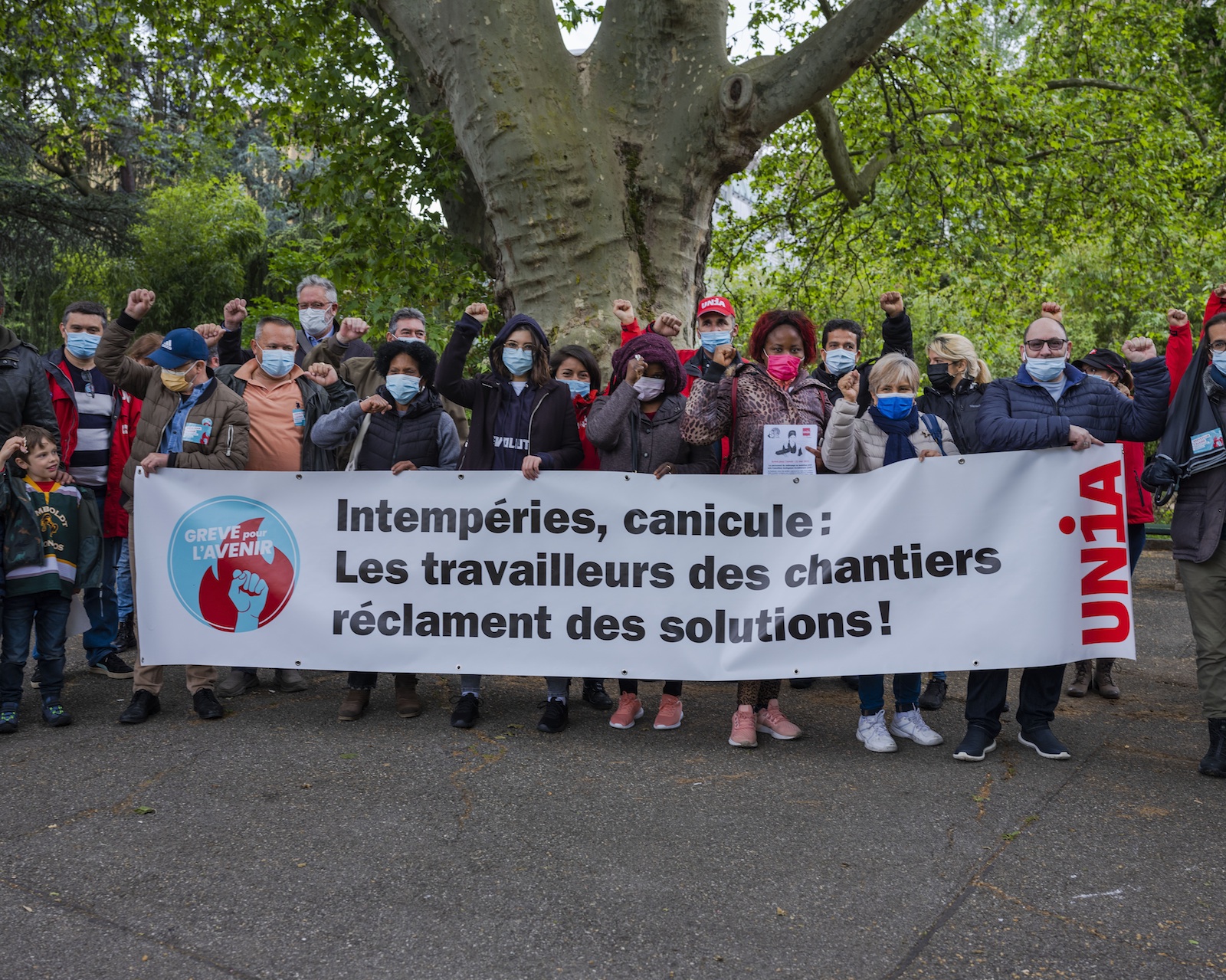 SecrÃ©taires syndicaux et militants rassemblÃ©s derriÃ¨re une banderole "IntempÃ©ries, canicule: les travailleurs des chantiers rÃ©clament des solutions."