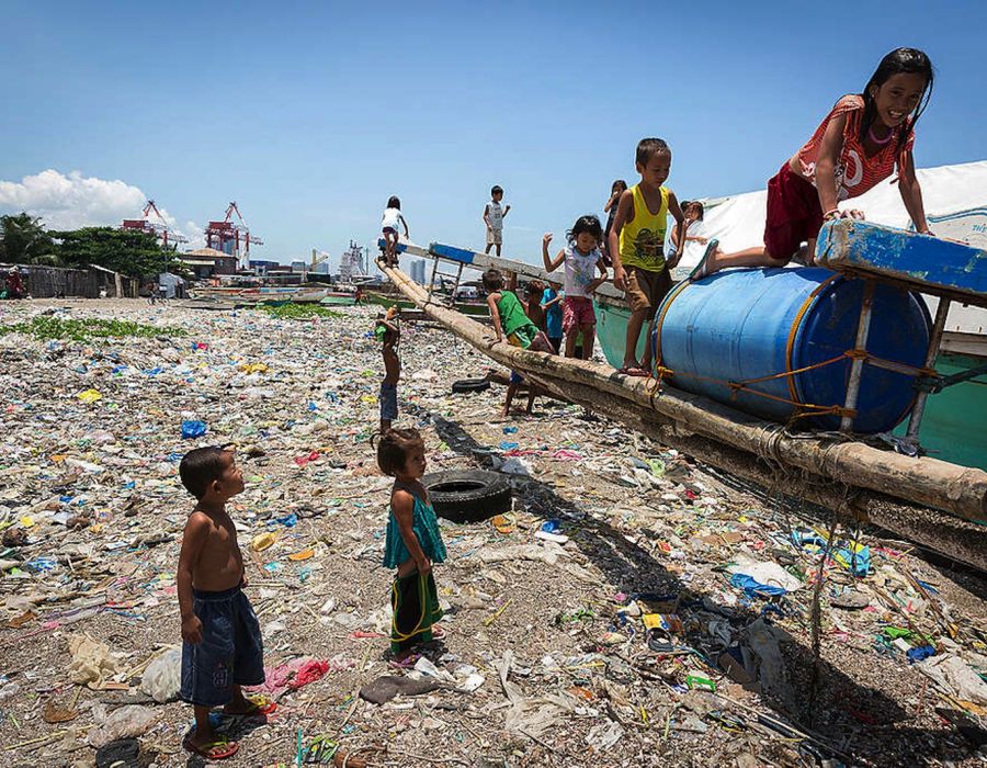 Des enfants jouant sur une plage envahie de plastique à Manille.