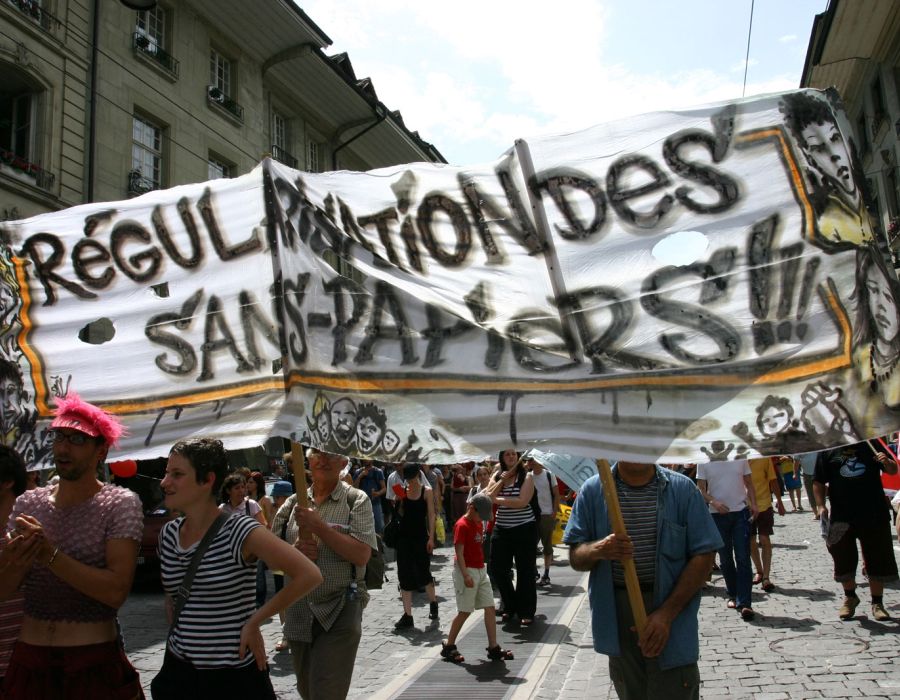 Manifestation dans les rues de Berne. On peut lire sur une grande banderole "Régularisation des sans-papiers".