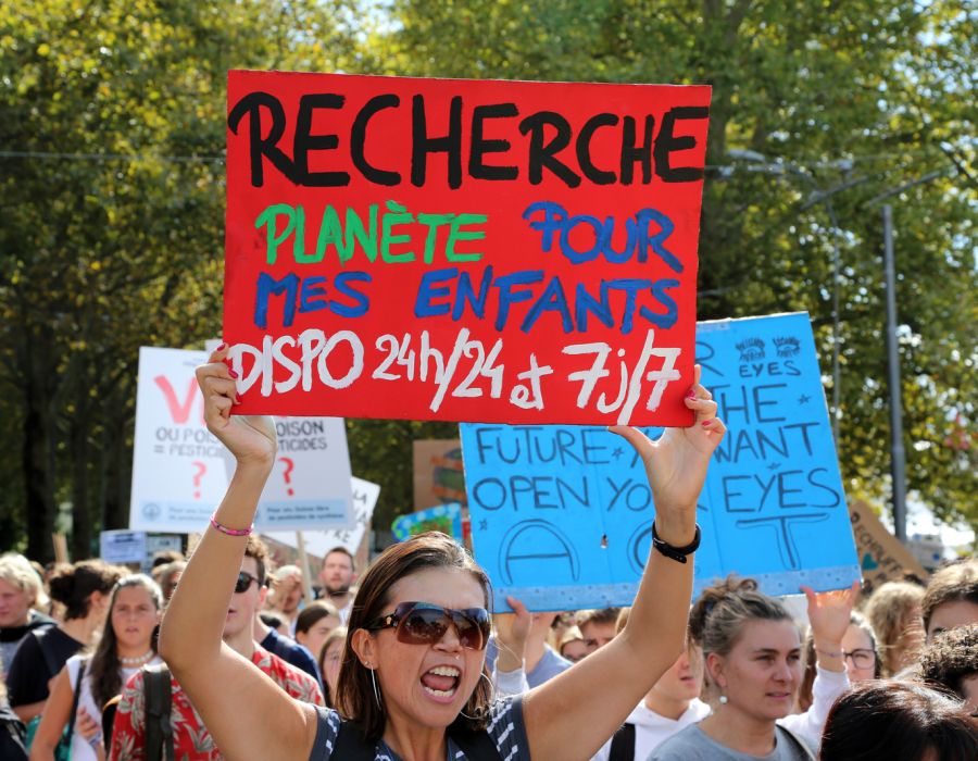 Manifestation pour le climat. Une femme brandit une pancarte sur laquelle on peut lire: Recherche planète pour mes enfants dispo 24h/24 et 7j/7.