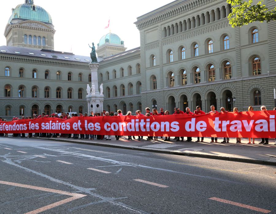 Banderole devant le palais fédérale: Défendons les salaires et les conditions de travail.