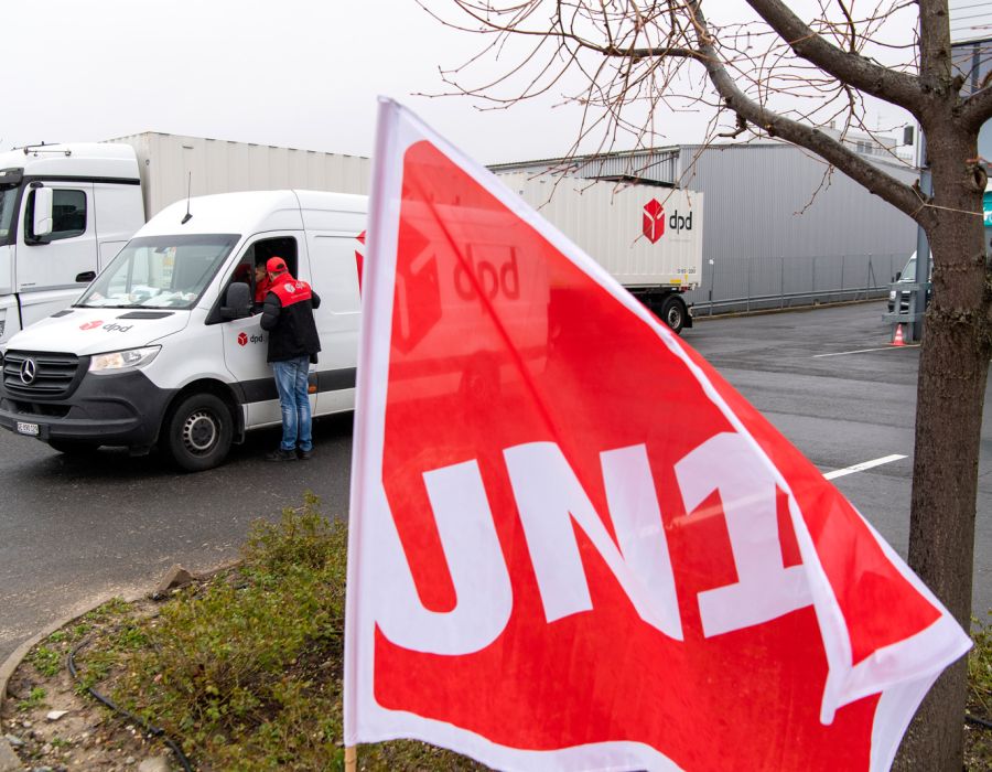 Un drapeau Unia flotte devant une camionnette de livraison.