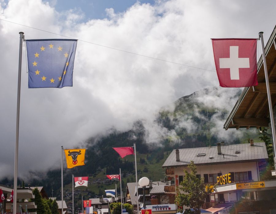 Un drapeau suisse et un drapeau européen se font face.
