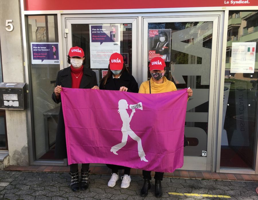 Trois femmes, casquettes Unia sur la tête, devant les locaux du syndicat à Genève.
