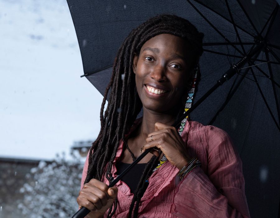 Portrait de Mireille Keïta-Gilgien, dans la neige, sous un parapluie.