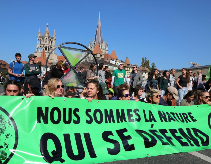 Action d'Extinction Rebellion à Lausanne. Sur une banderole on peut lire: "Nous sommes la nature qui se défend."