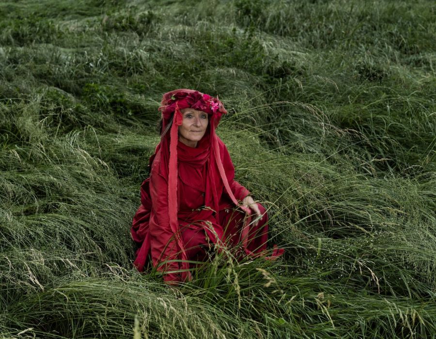 Portrait de Colette Bugnon, en tenue rouge, au milieu d'un champ.