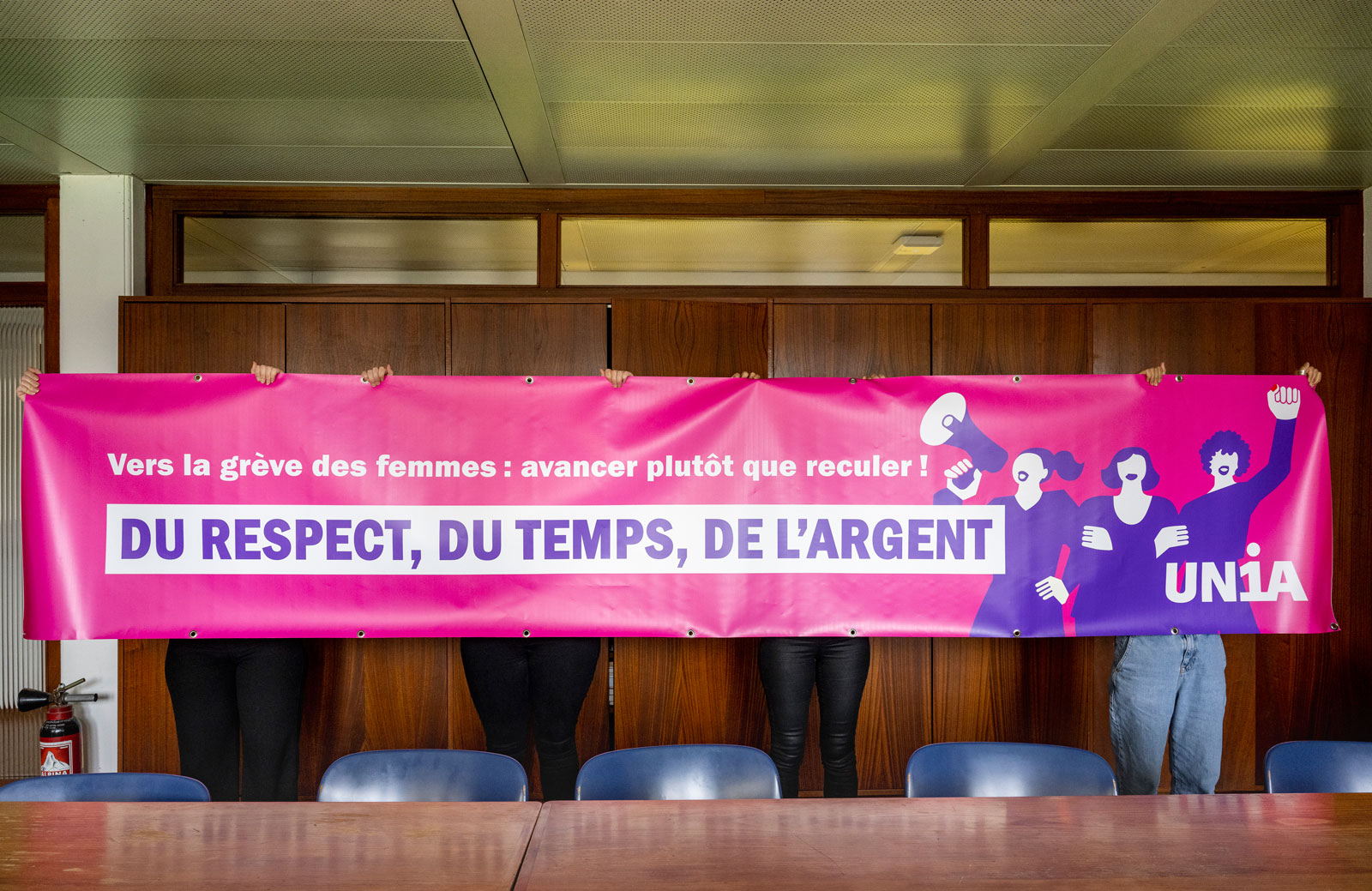 Les quatre femmes cachées derrière une banderole Unia "Du respect, du temps, de l'argent".