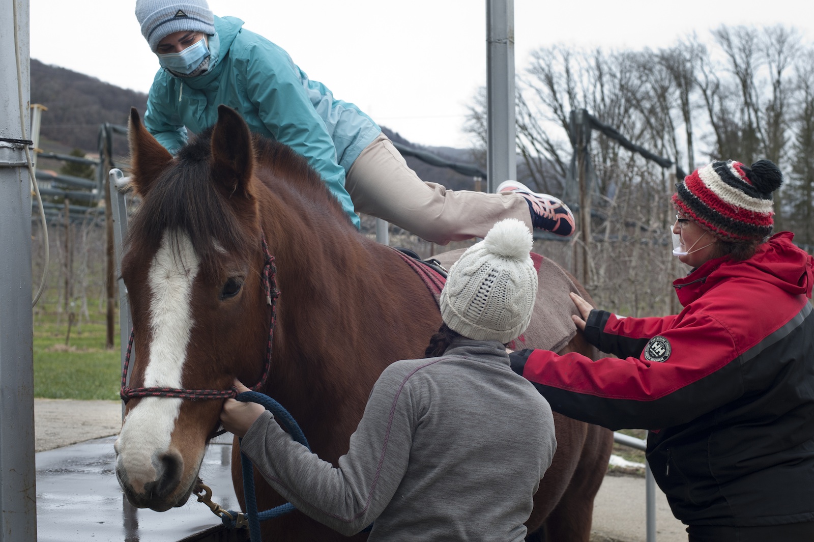 Une patiente monte sur le cheval avec l'aide des soignantes.