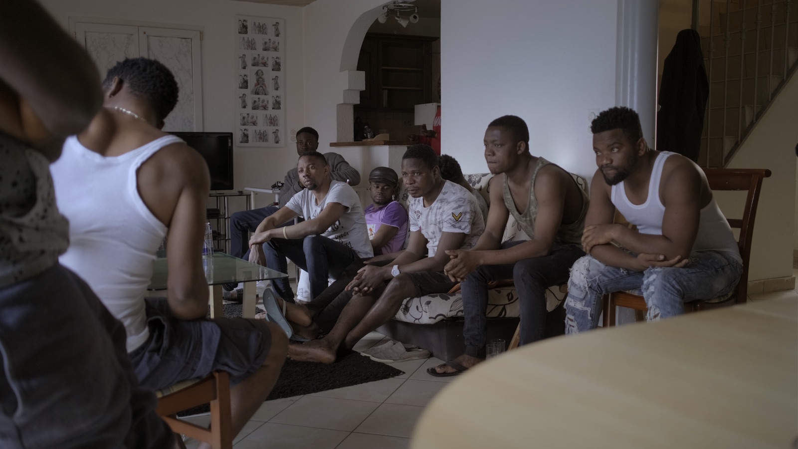 Image tirée du documentaire. Plusieurs hommes en discussion dans un séjour.