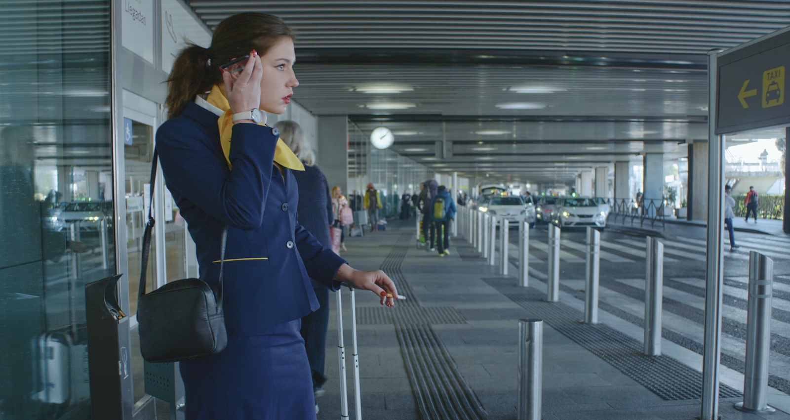 Image tirée du film: une hôtesse de l'air fume une cigarette.