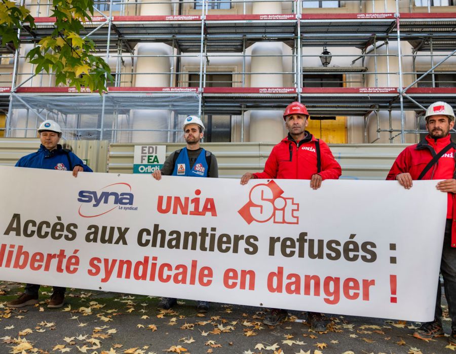 Des syndicalistes brandissent une banderole sur laquelle on peut lire: Accès aux chantiers refusés: liberté syndicale en danger!