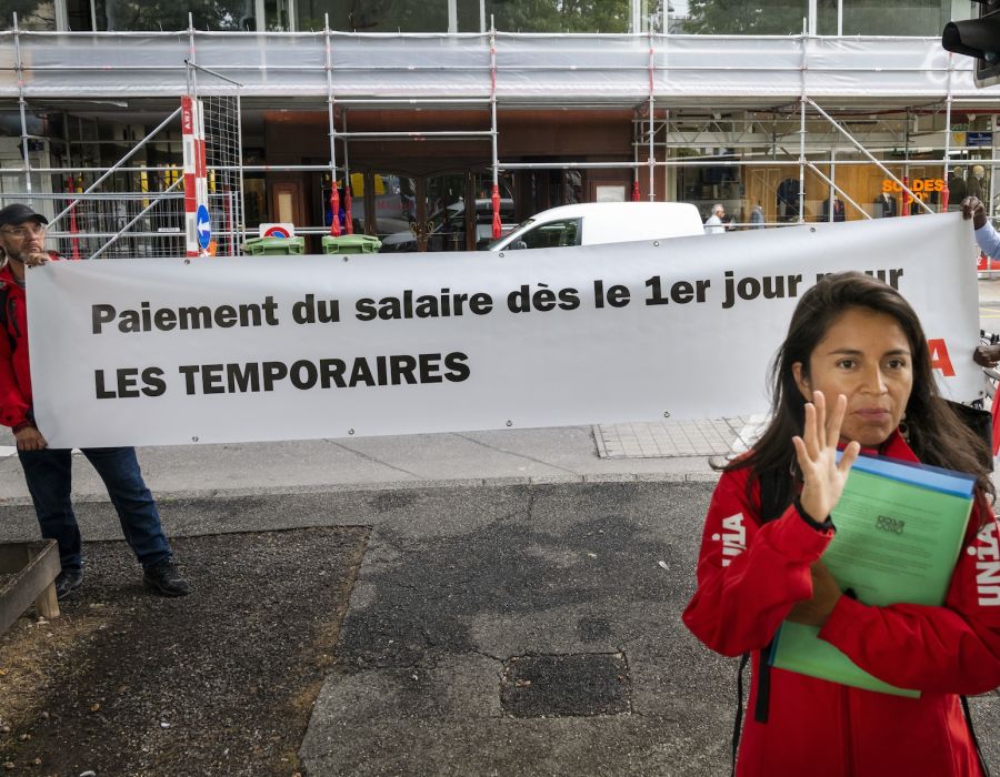 Syndicaliste d'Unia devant une banderole: "Paiement du salaire dès le 1er jour pour les temporaires."