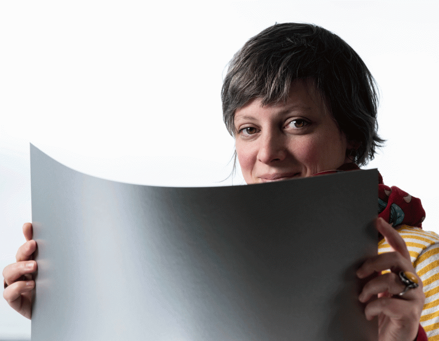 Portrait de l'illustratrice Adrienne Barman derrière une grande page blanche.