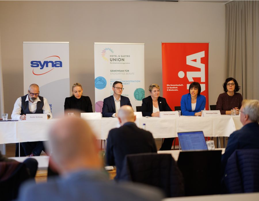 Personnes assises à une table lors d'une conférence de presse.