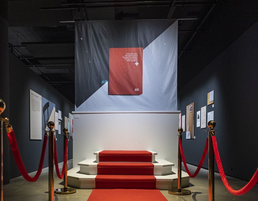 Exposition avec un passeport suisse géant au bout d'un tapis rouge.