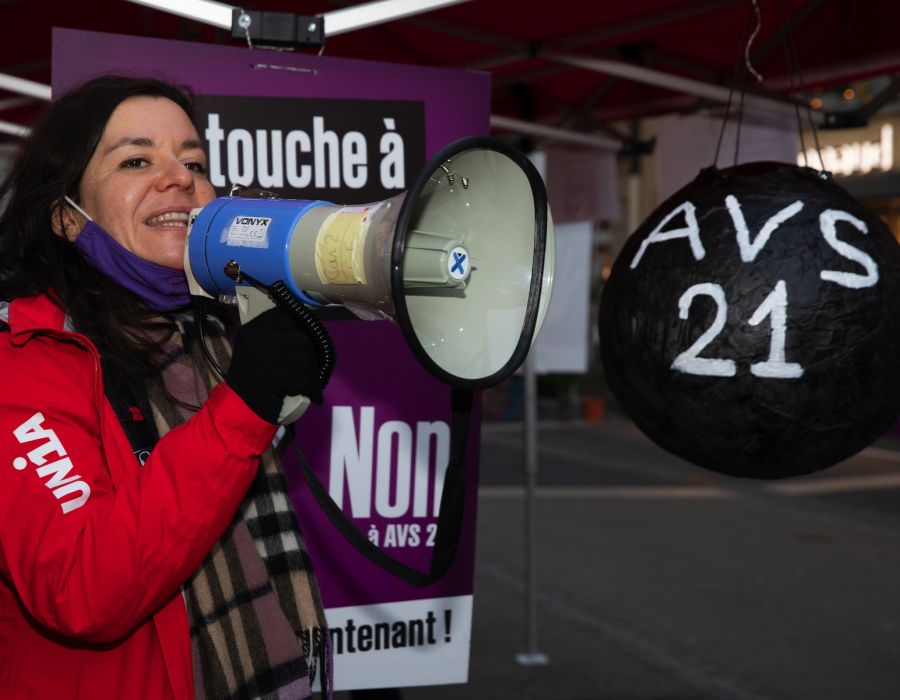 Une secrétaire syndicale d'Unia, mégaphone à la main. A ses côtés une piñata "AVS 21" à briser.