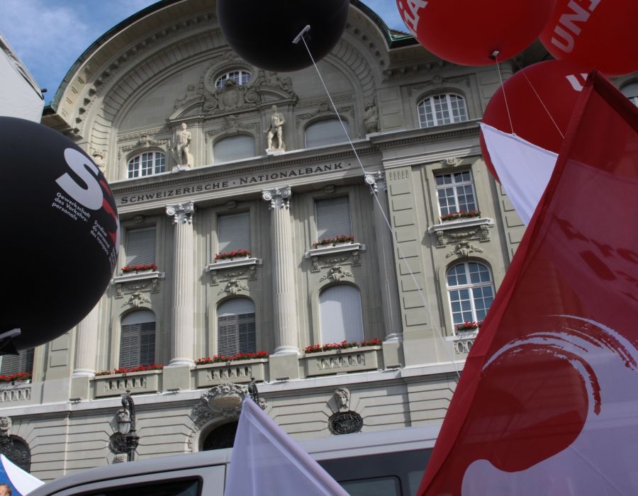 Des drapeaux syndicaux flottent autour du bâtiment de la Banque nationale suisse.