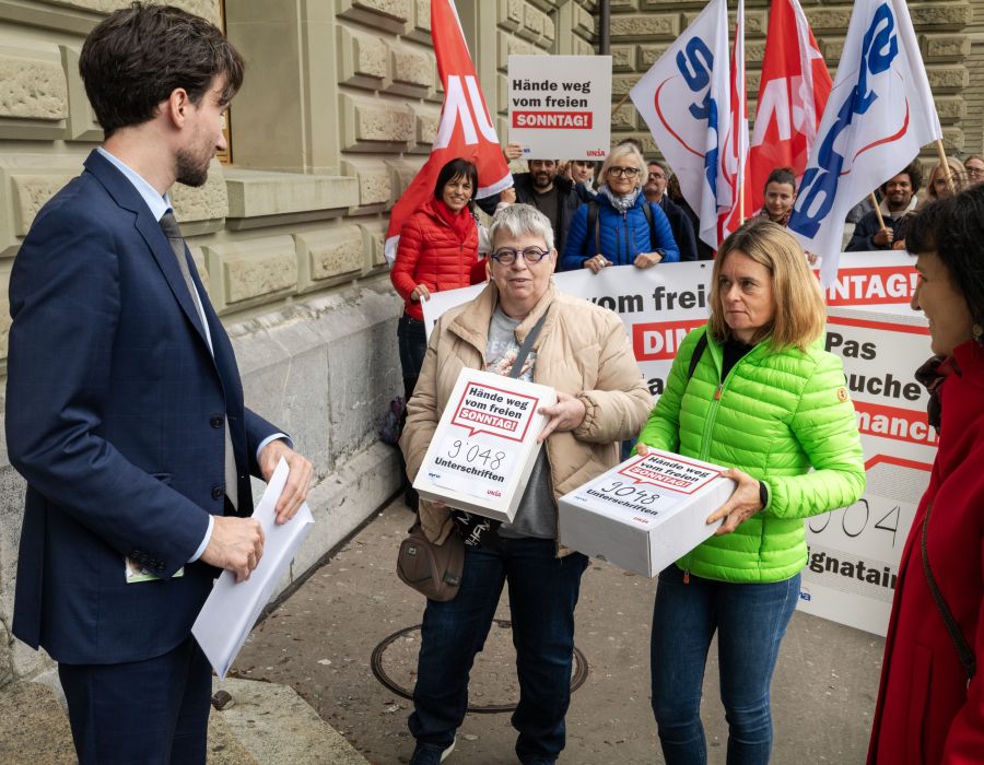 Des personnes remettent des cartons avec les feuilles de la pétition.