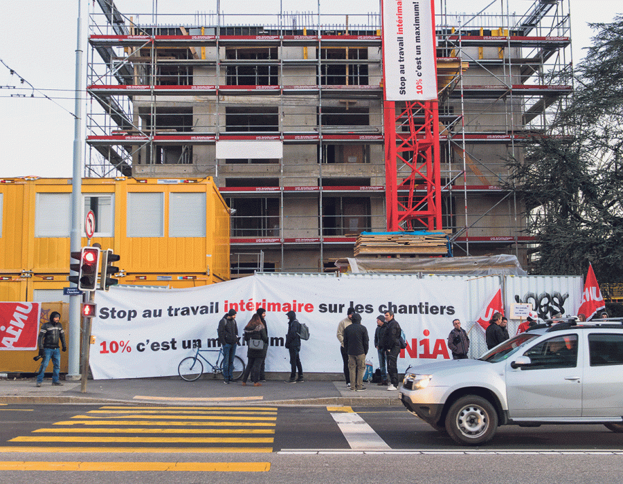 Une banderole Unia disant stop au travail intérimaire sur les chantiers déroulée devant un bâtiment en construction.