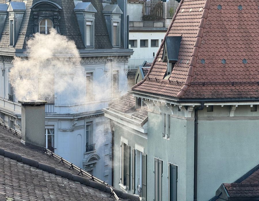 Cheminée sur toit de maison fumante.